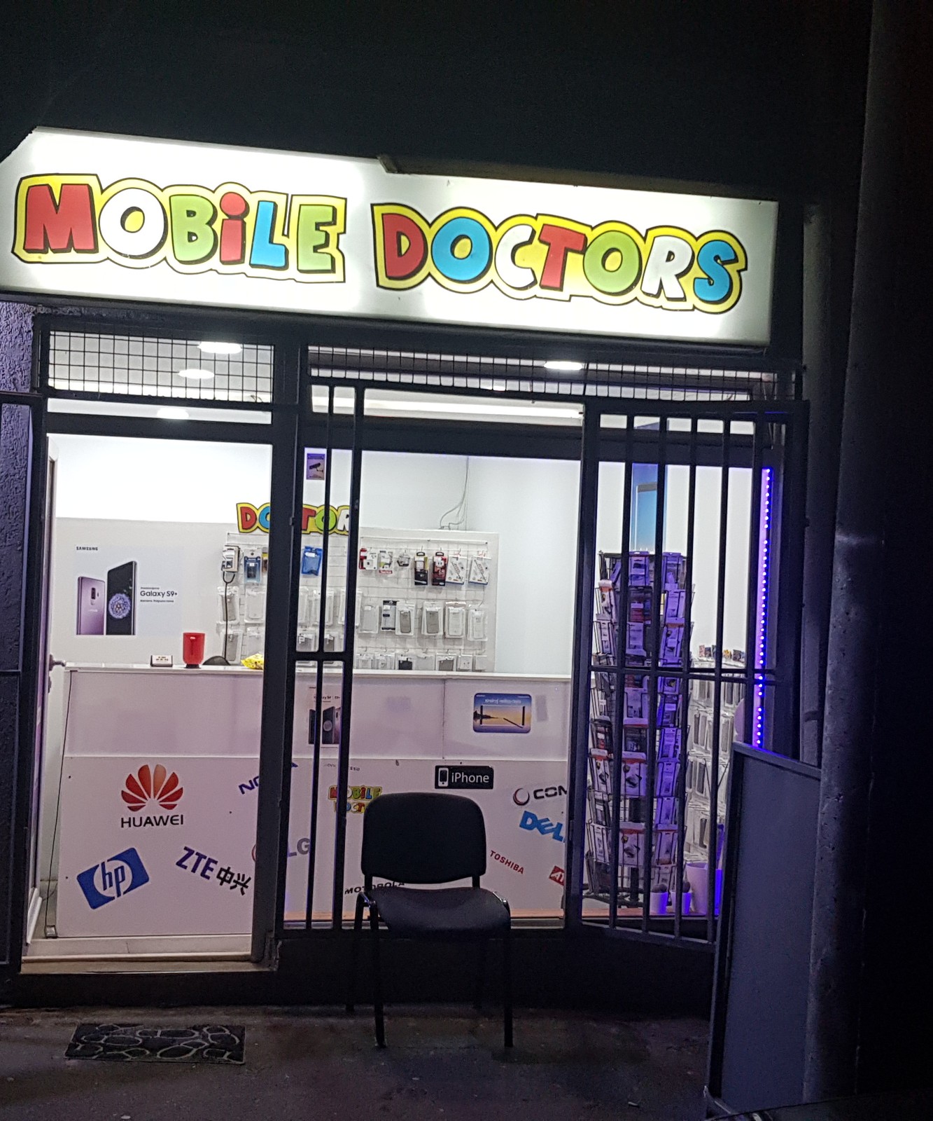 Osvetljen natpis Mobile Doctor iznad ulaza u radnju noću