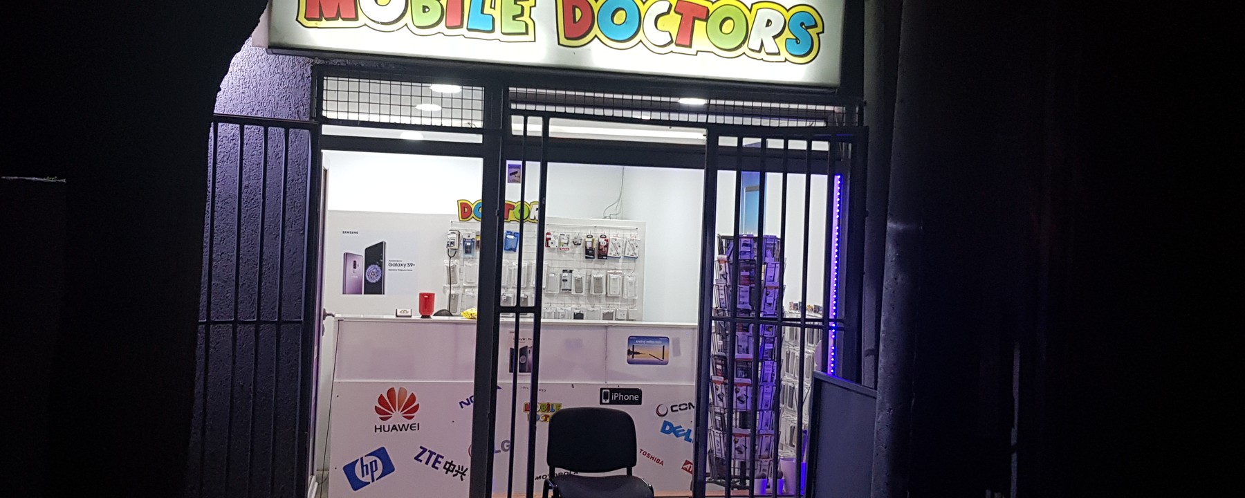 Osvetljen natpis Mobile Doctor iznad ulaza u radnju noću